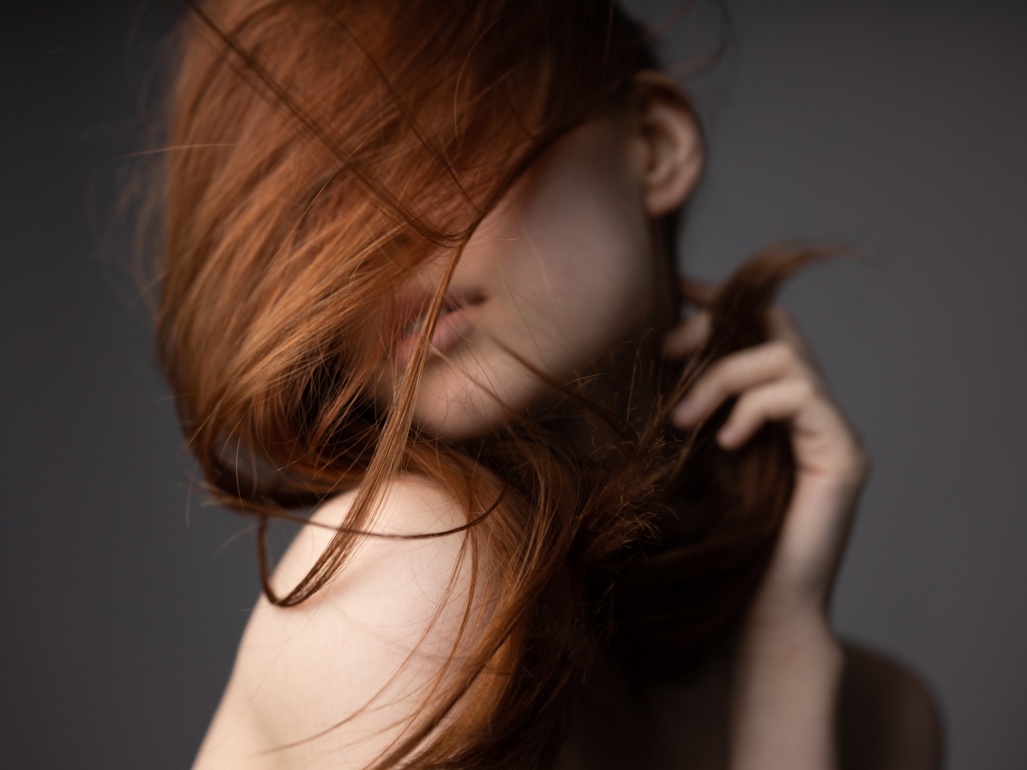 Copper red hair moving across a woman's face in an editorial beauty portrait